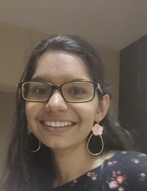 Anarghya, from A4E's Advisory Panel, wears flower loop earrings and smiles at the camera.